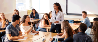 Teacher lecturing a group of students in a classroom setting.