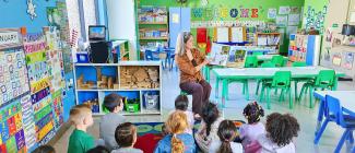 PHSC female staff member reading books to children.